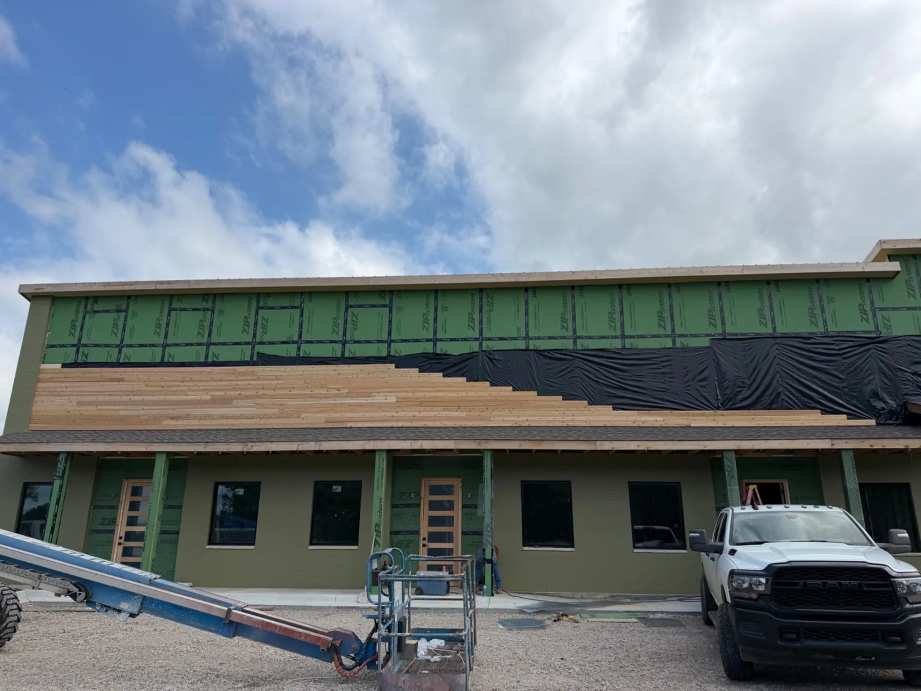 Exterior of the Ivory Blossom Salon building under construction in Broken Arrow, with cedar siding going up over the entry