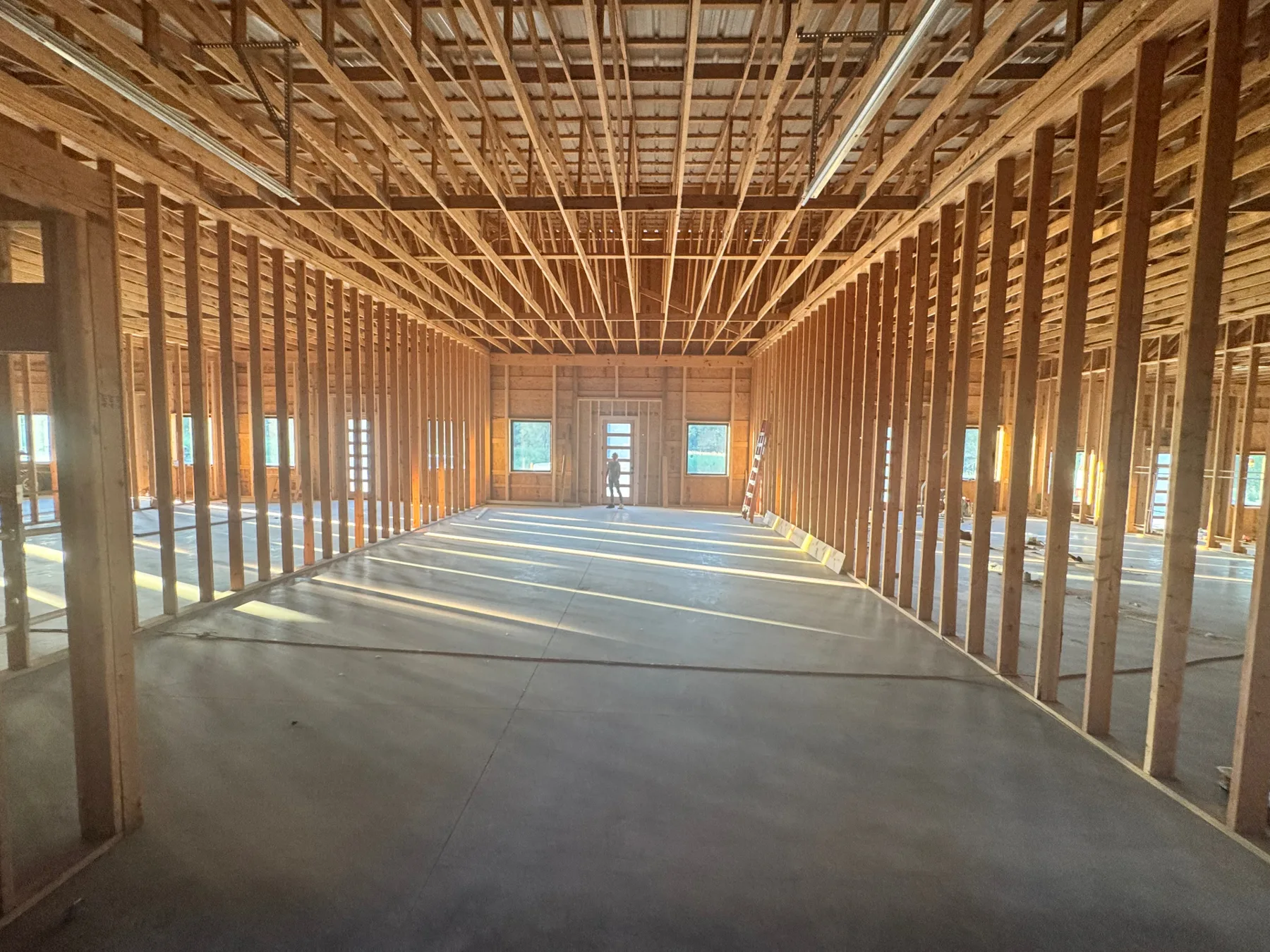 Framed interior of the future Ivory Blossom Salon styling floor, sunlight falling across the poured concrete slab