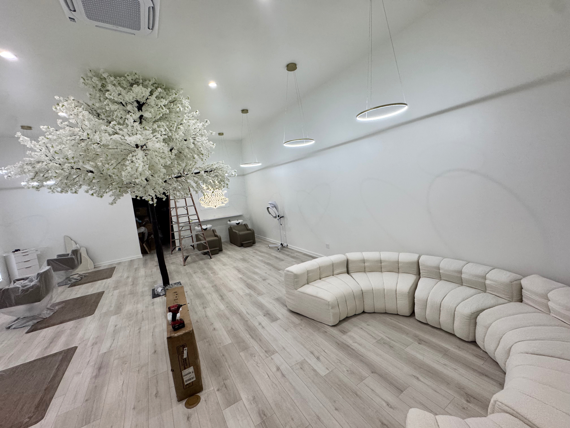Wide view of the Ivory Blossom Salon interior with curved lounge, blossom tree and styling stations